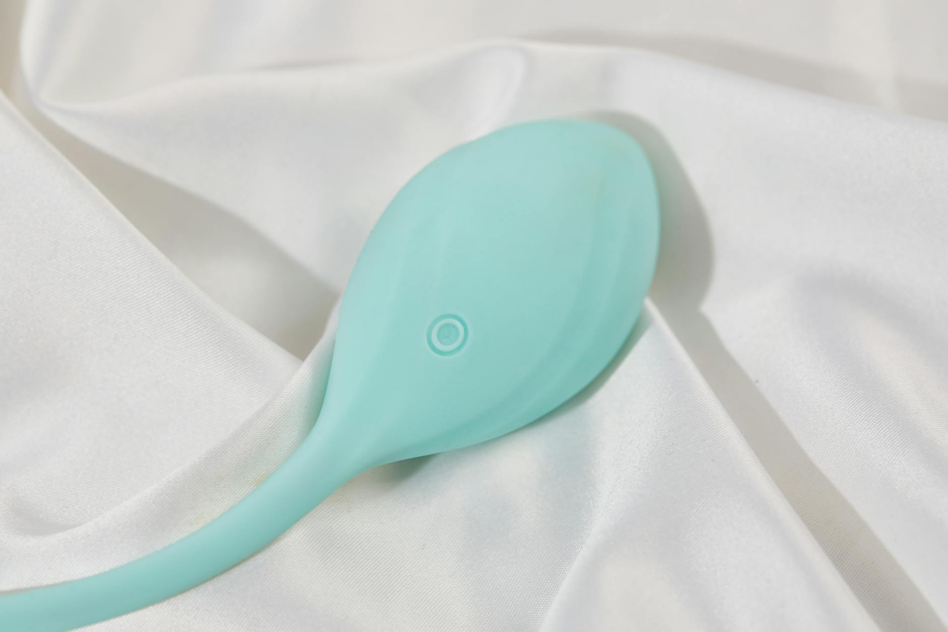 A teal lemon vibrator on soft white silk fabric, representing gentle clitoral pleasure