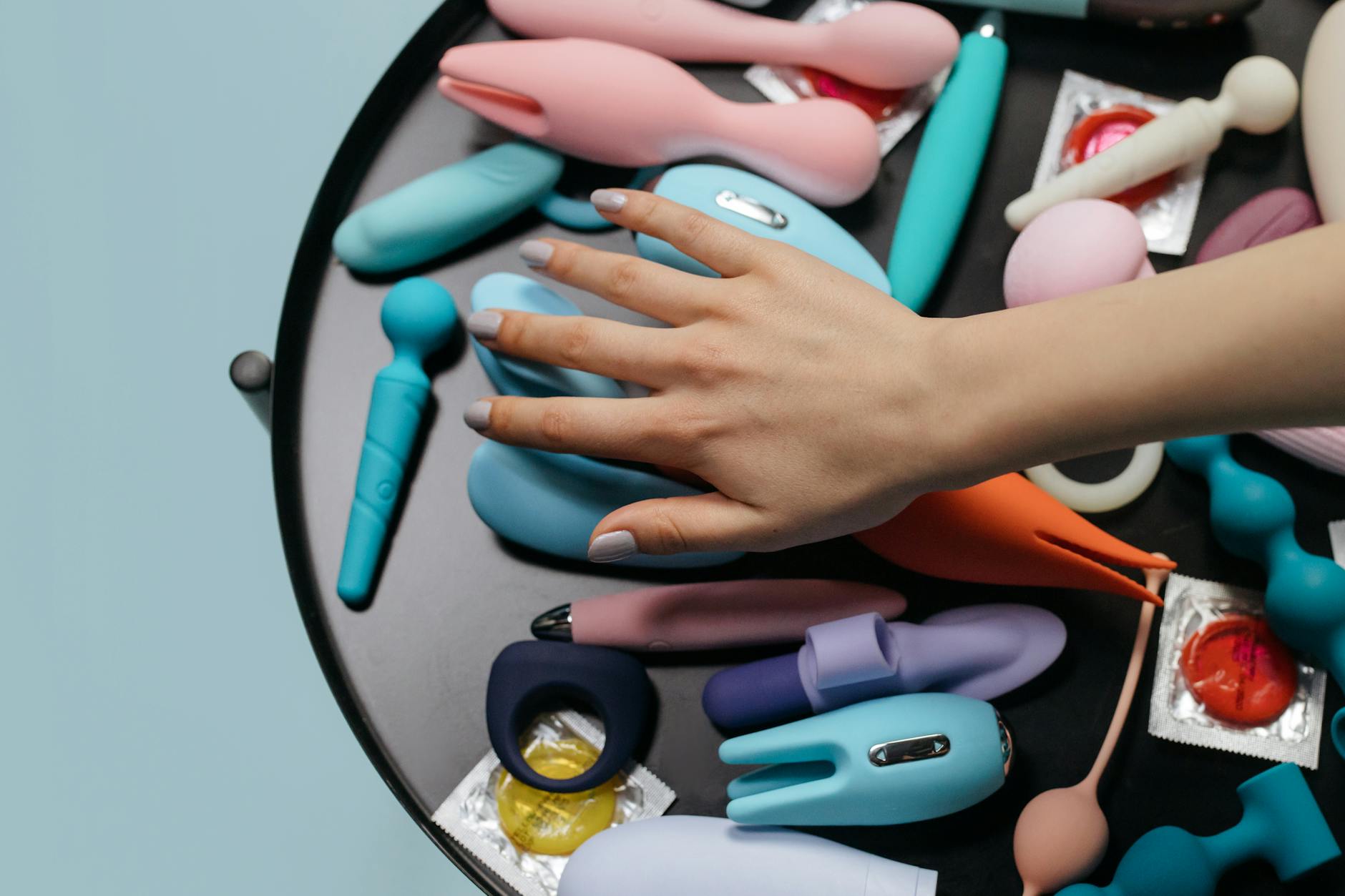 Woman holding colorful clitoral vibrators in a contemplative pose