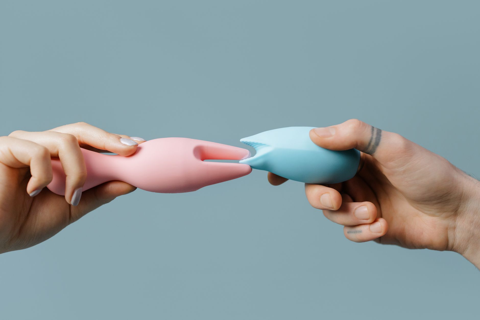 Close-up of vibrant clitoral vibrators in various colors held in hands
